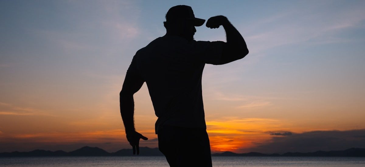a silhouette of a man standing on a beach at sunset