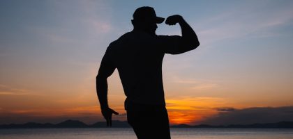 a silhouette of a man standing on a beach at sunset