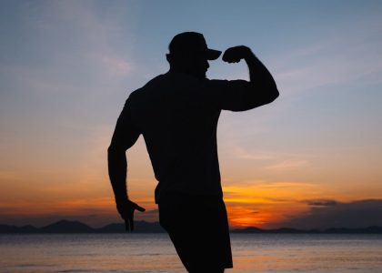 a silhouette of a man standing on a beach at sunset